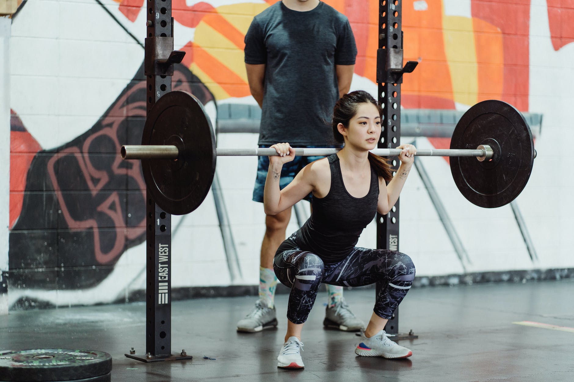 a woman lifting a barbell with plates
