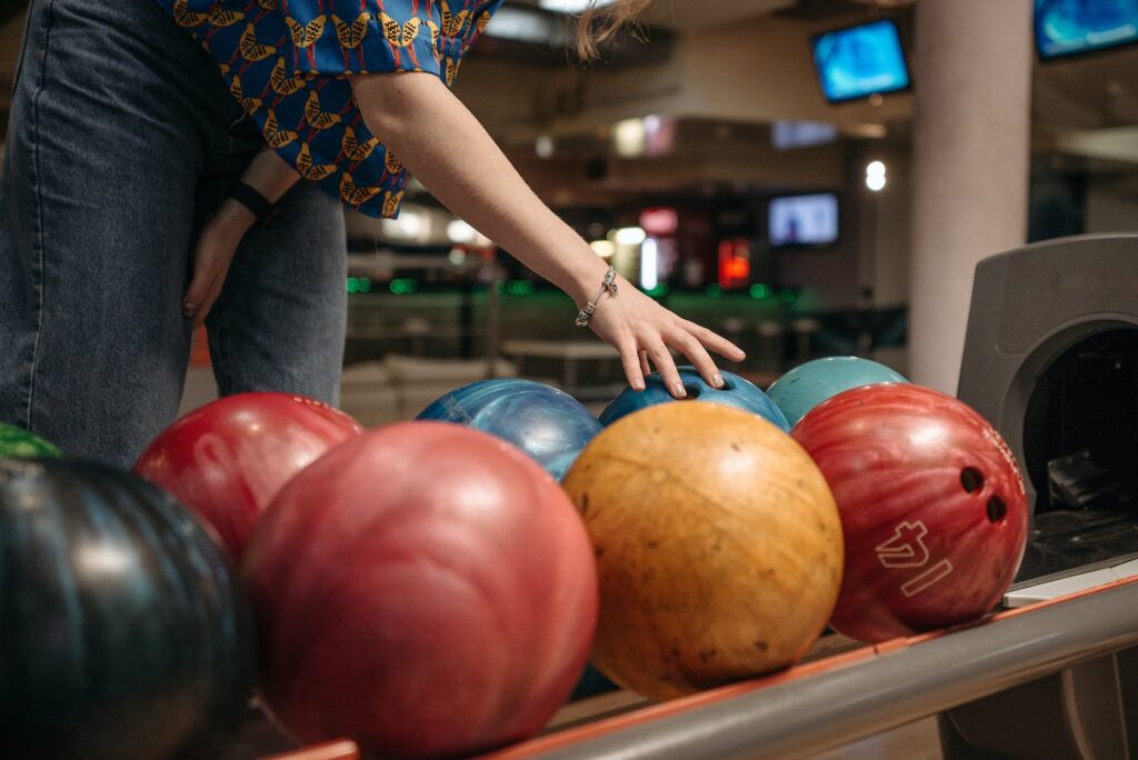 person in blue and yellow shirt holding blue bowling ball